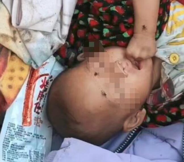 网传视频显示，女婴躺在杂物中，有苍蝇在脸上爬行